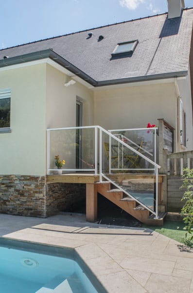 Un escalier jouxte l'agrandissement et la terrasse en bois